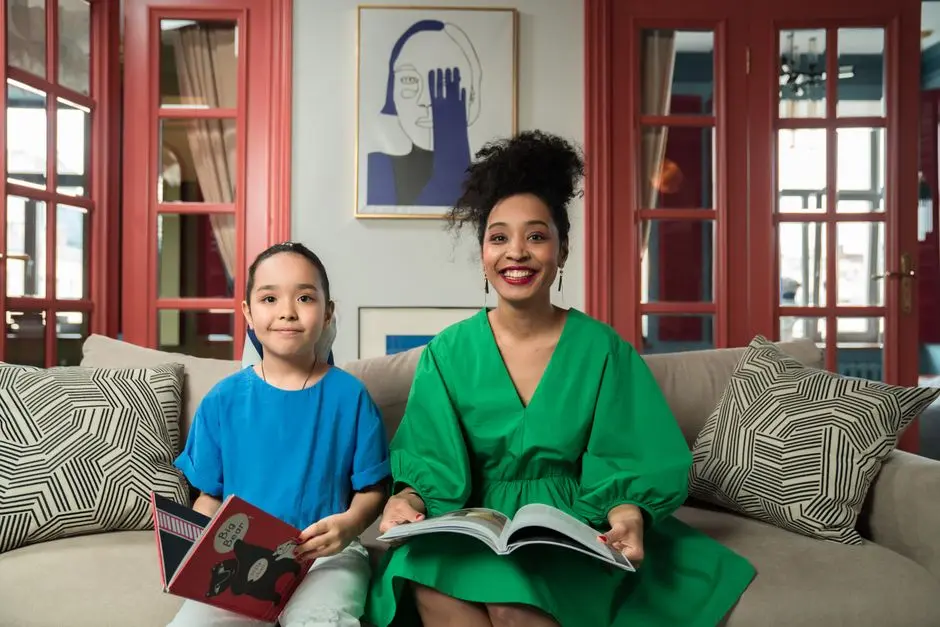 Seorang ibu dan anak remaja duduk di sofa saling tersenyum